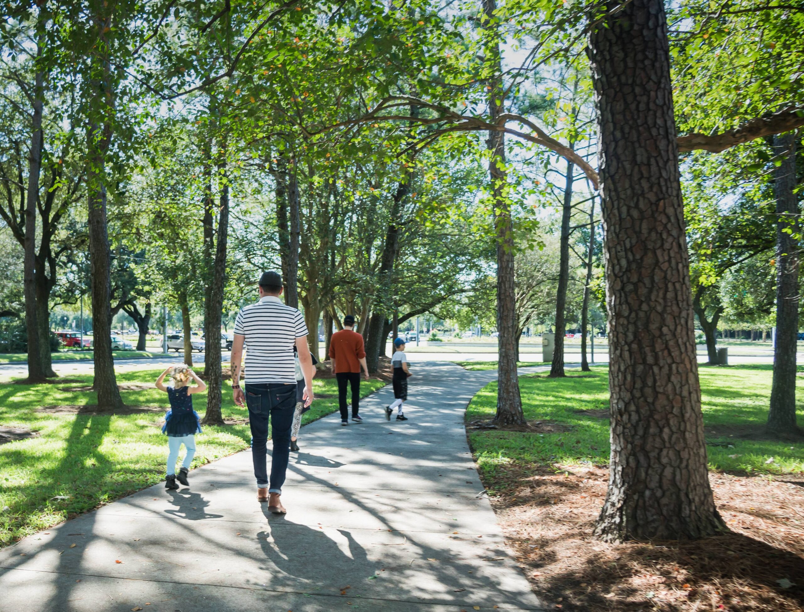 family walking on shaded park path scaled
